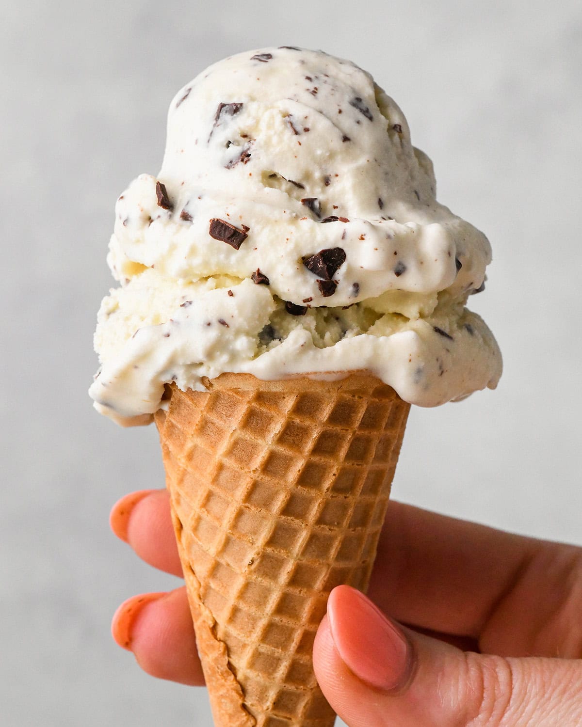 a hand holding an ice cream cone with Mint Chocolate Chip Ice Cream 