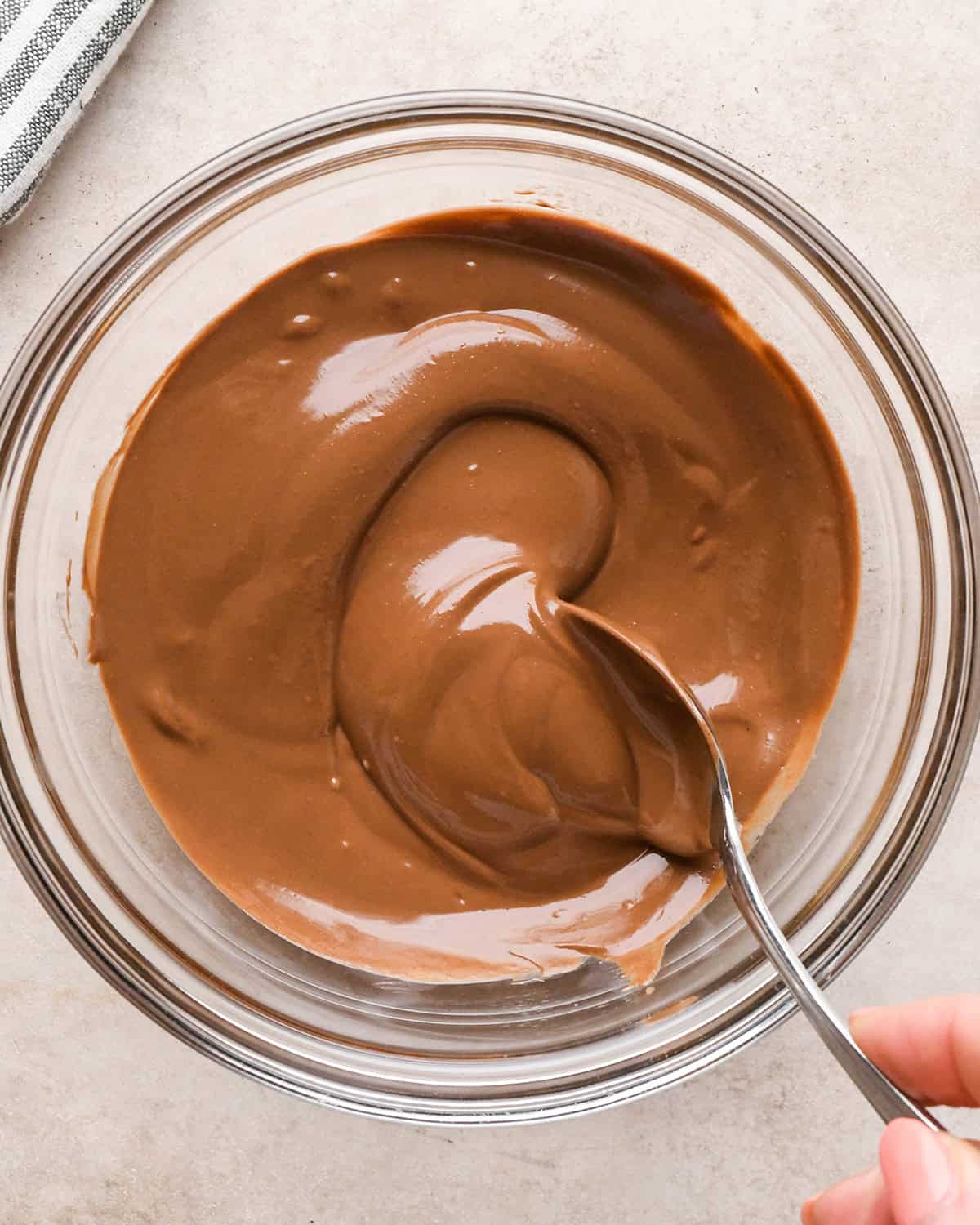 a spoon stirring melted chocolate peanut butter mixture