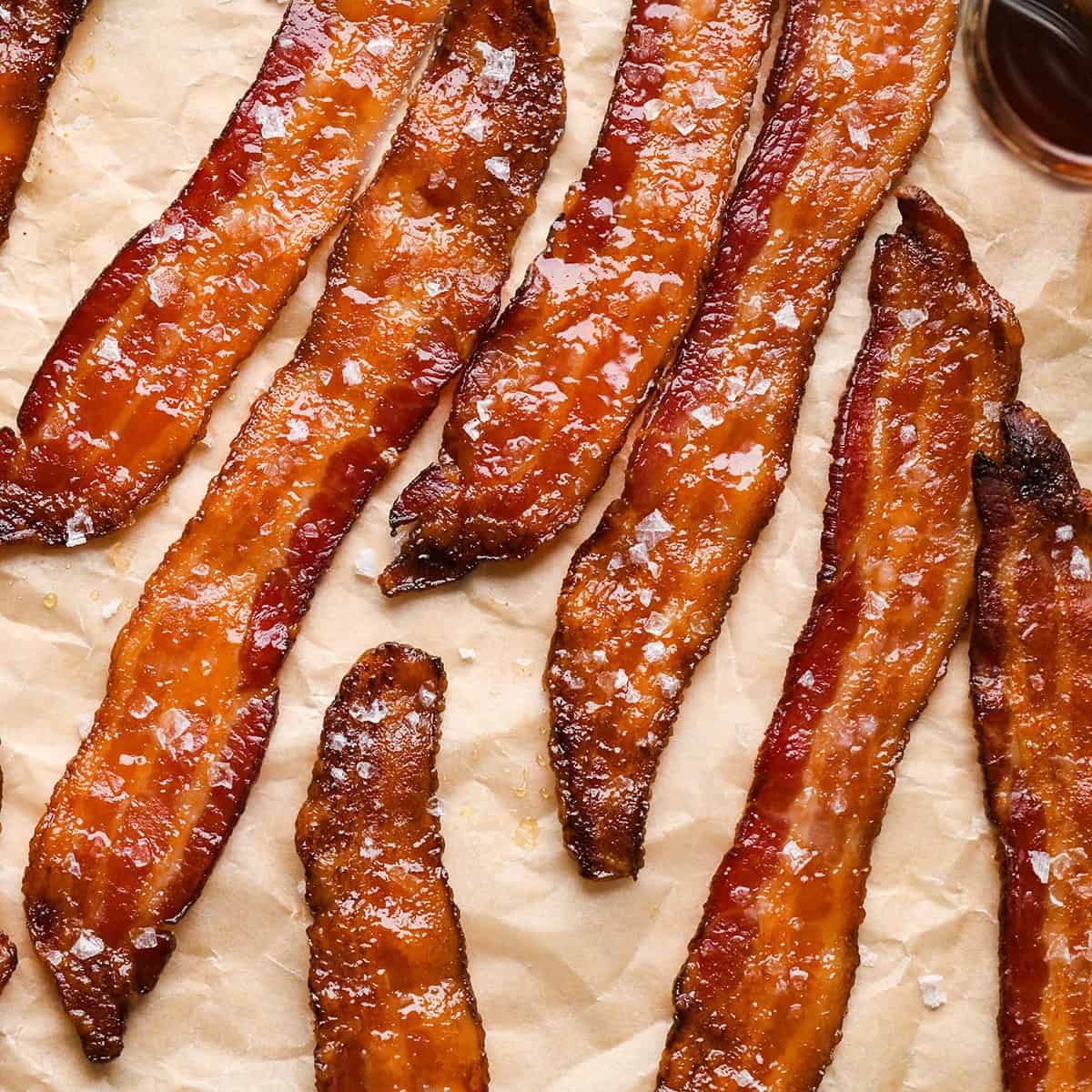 Crispy maple bacon topped with sea salt on parchment paper