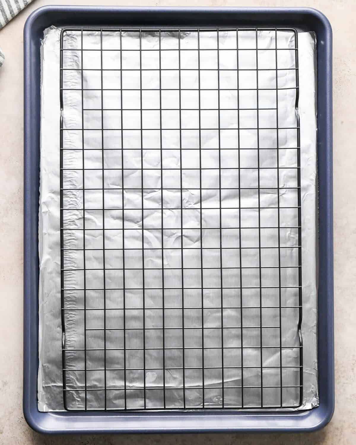 Making maple bacon - overhead photo of a baking sheet topped with tin foil and a cooling rack