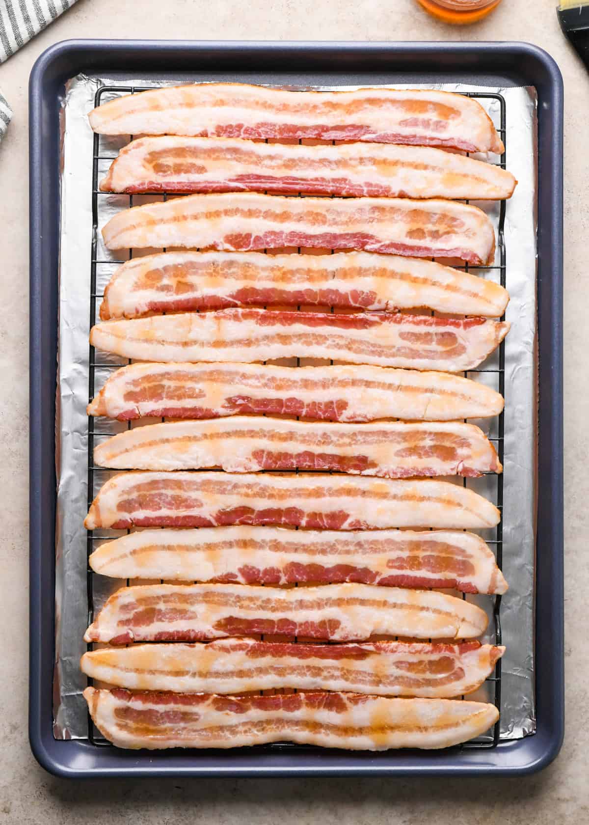 Making maple bacon - overhead photo of bacon strips on a baking sheet coated with maple syrup and ready to cook