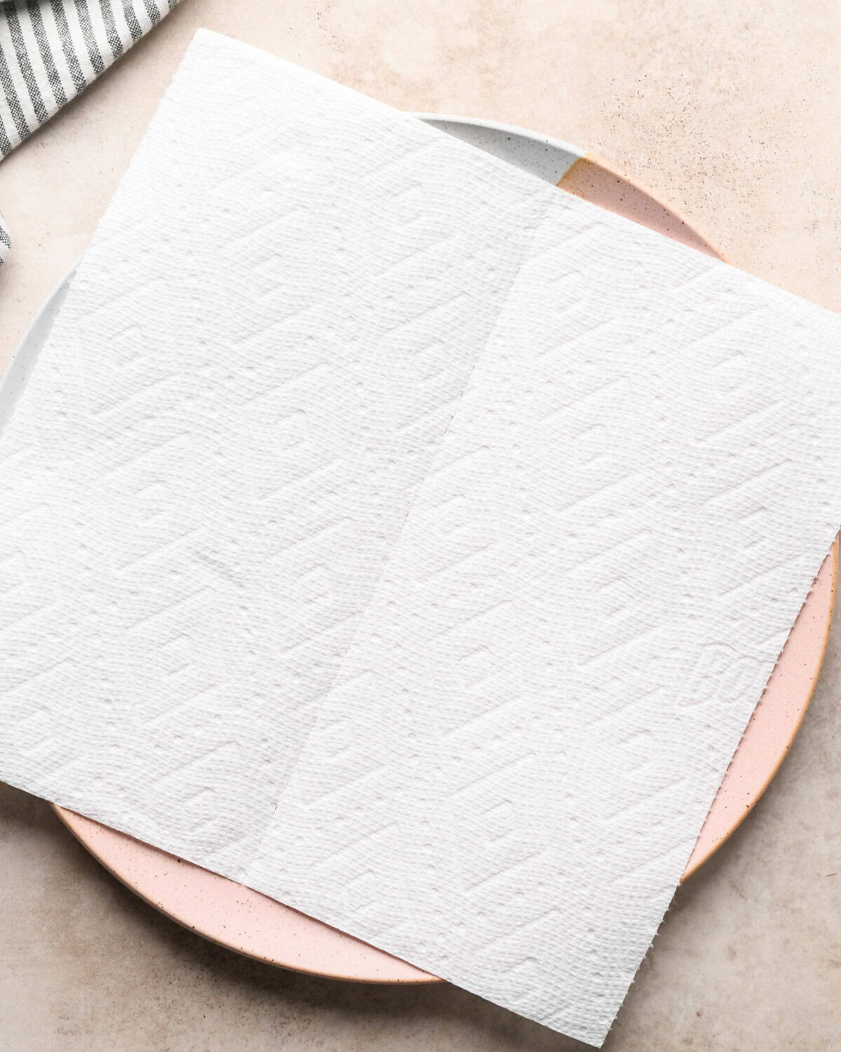Making maple bacon - overhead photo of a white-and-pink speckled plate covered by 2 paper towels