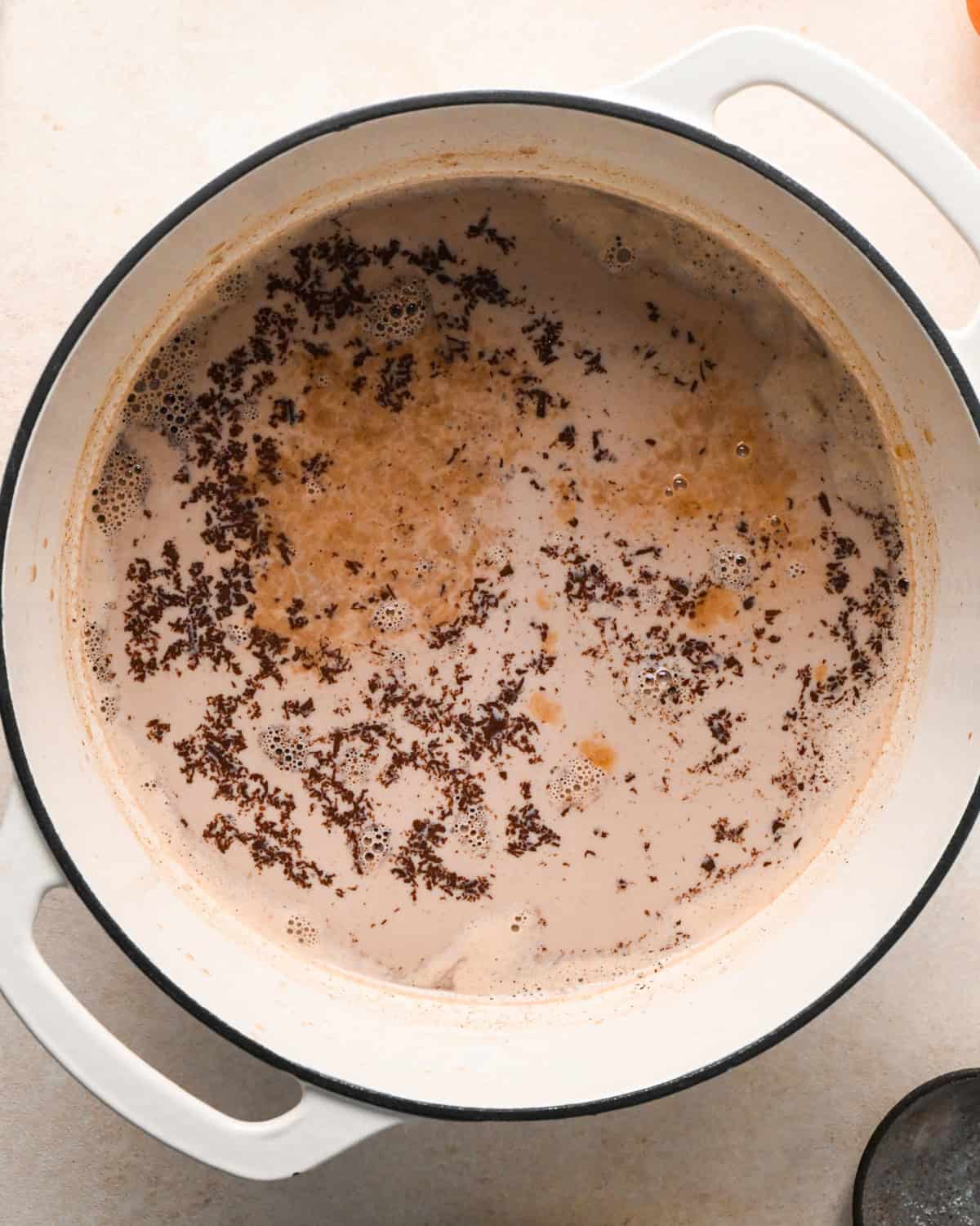 pumpkin spice hot chocolate ingredients in a white pot before whisking