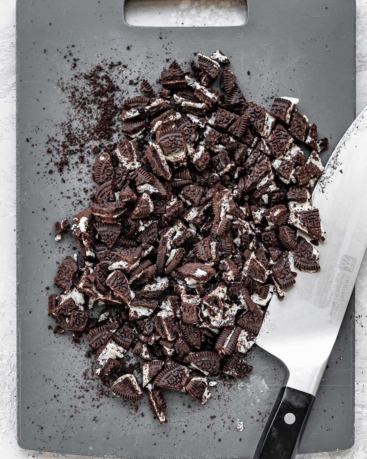 oreos chopped into large pieces on a cutting board with a knife