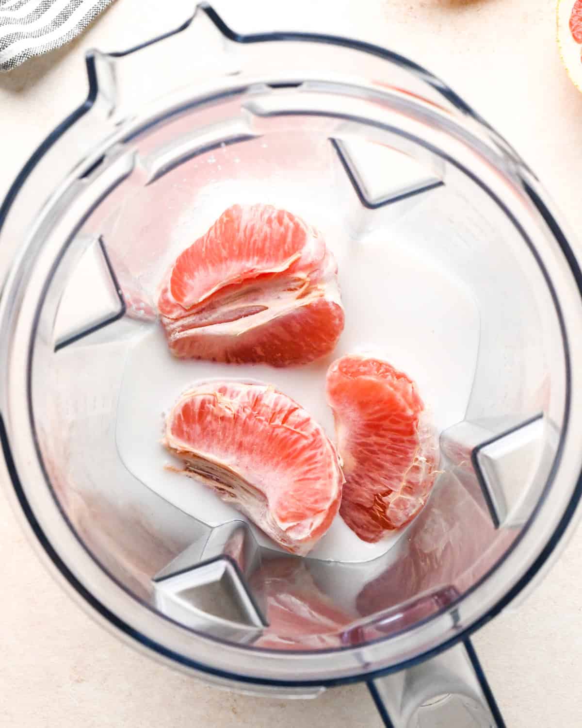 making a grapefruit smoothie: overview photo of milk and grapefruit in a blender.