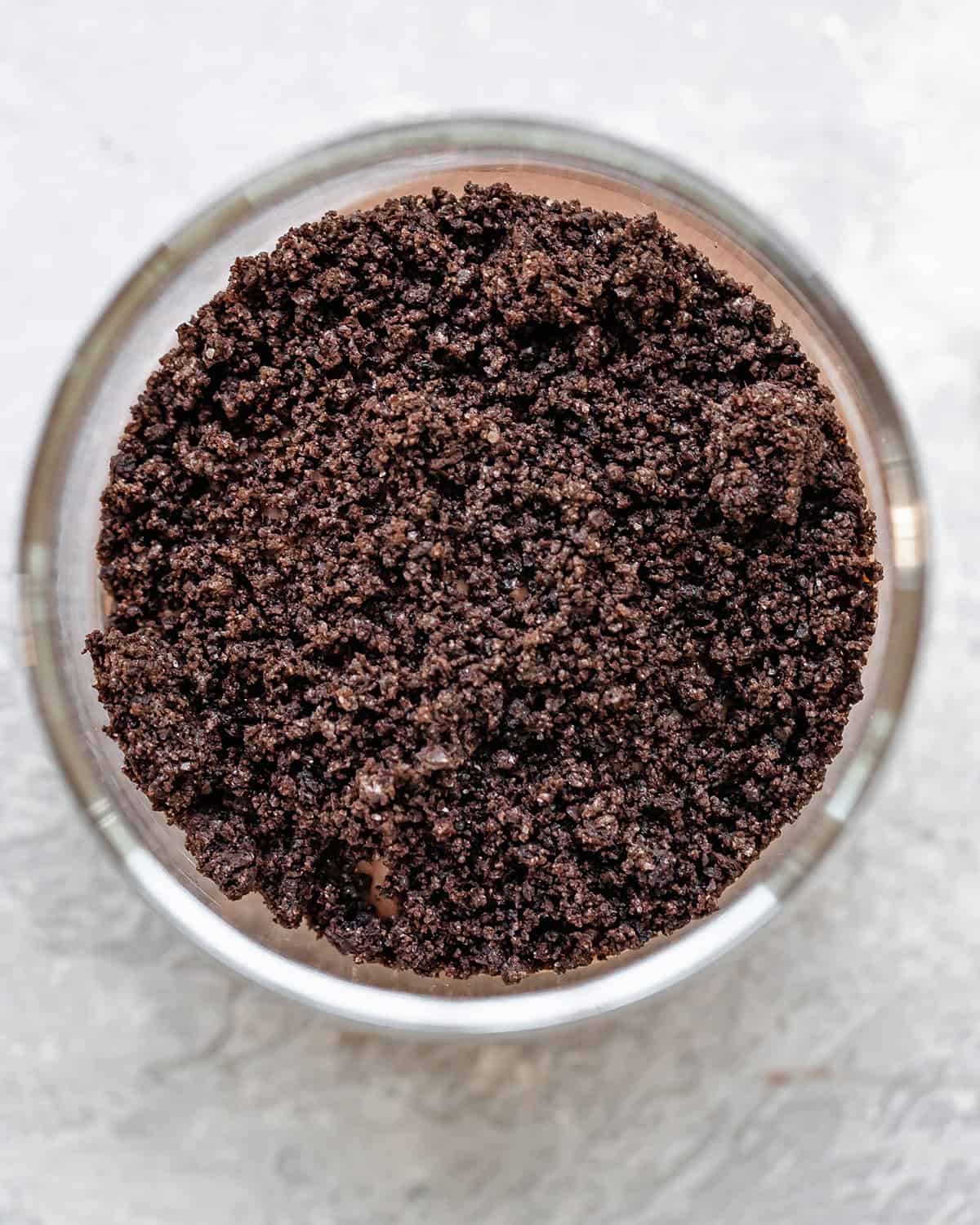 assembling dirt cups - cookie crumbs on top of the first layer of pudding