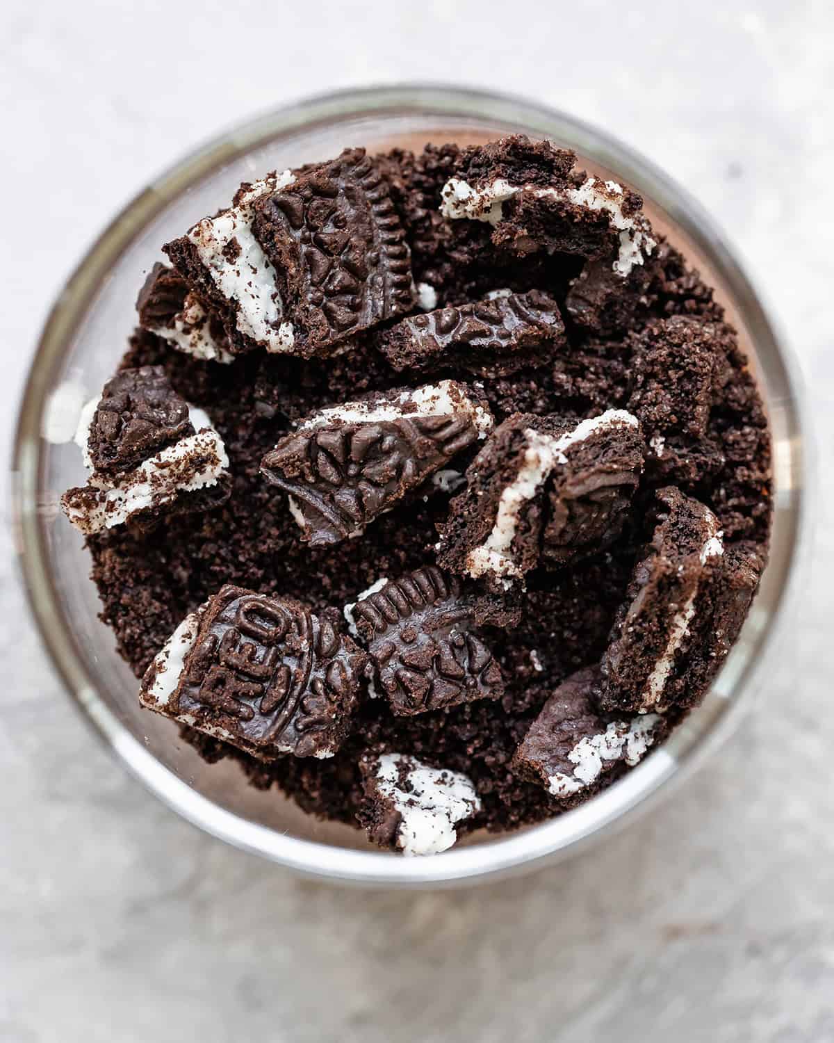 assembling dirt cups - chopped cookies on top of the cookie crumbs