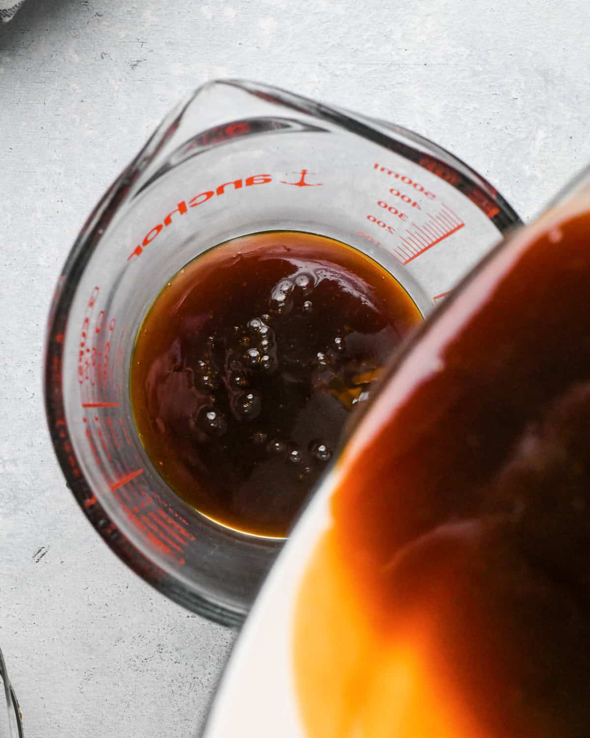Making teriyaki sauce: overhead photo of sauce being poured into a clear glass measuring cup.