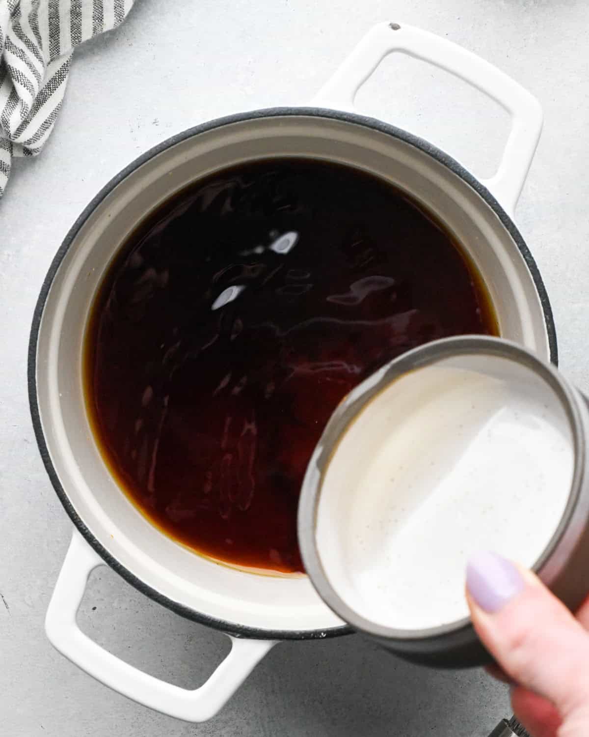 Making teriyaki sauce: continuing to add the ingredients to a white skillet.