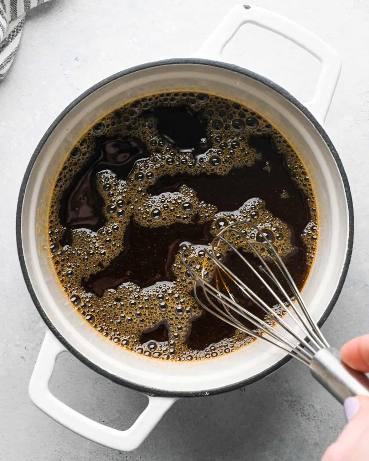 Making teriyaki sauce: overhead photo of sauce ingredients in a white skillet being whisked together.