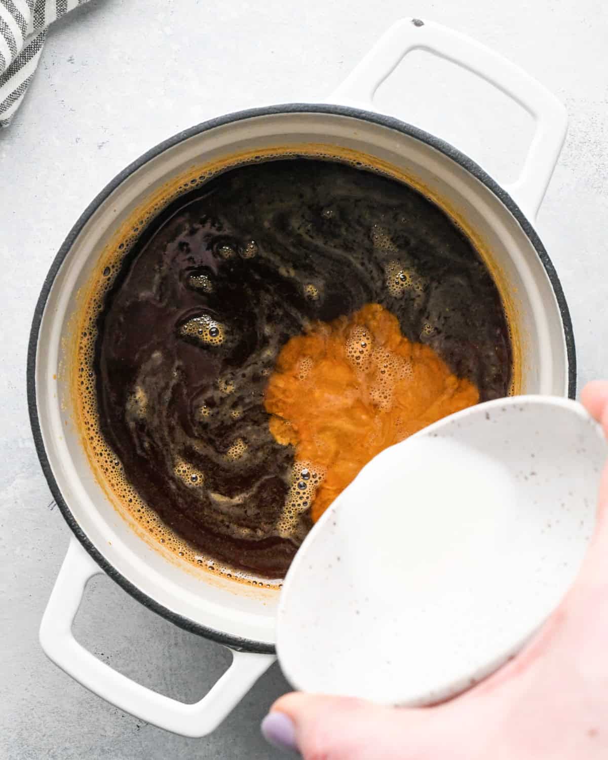 Making teriyaki sauce: overhead photo of cornstarch and water being added to the white skillet with the remaining ingredients.