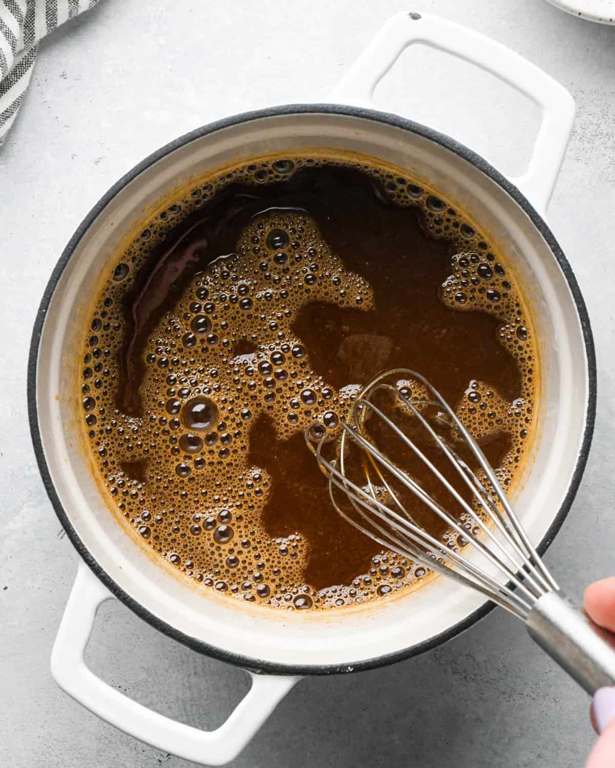 Making teriyaki sauce: overhead photo of all ingredients in a white skillet being whisked together.