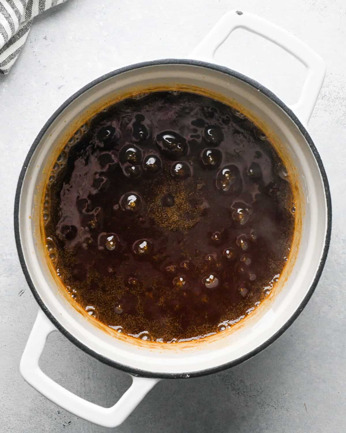 Making teriyaki sauce: overhead photo of sauce beginning to simmer in a white skillet.
