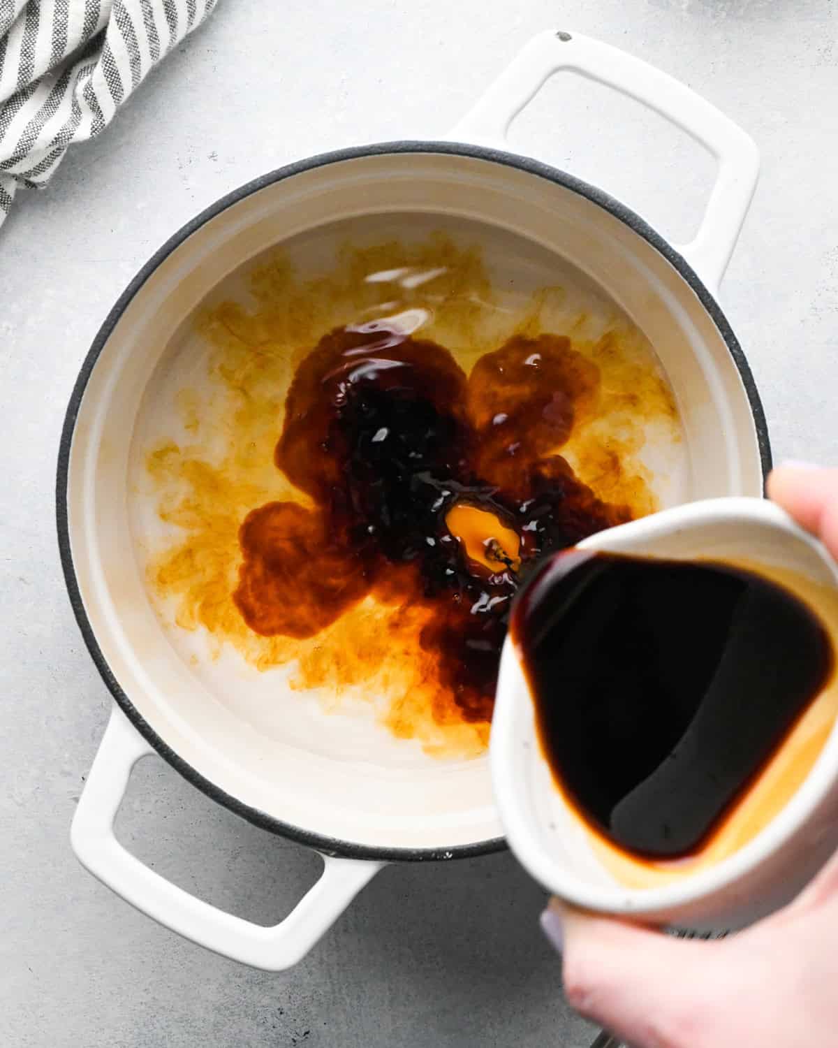 Making teriyaki sauce: beginning to add the ingredients to a white skillet.