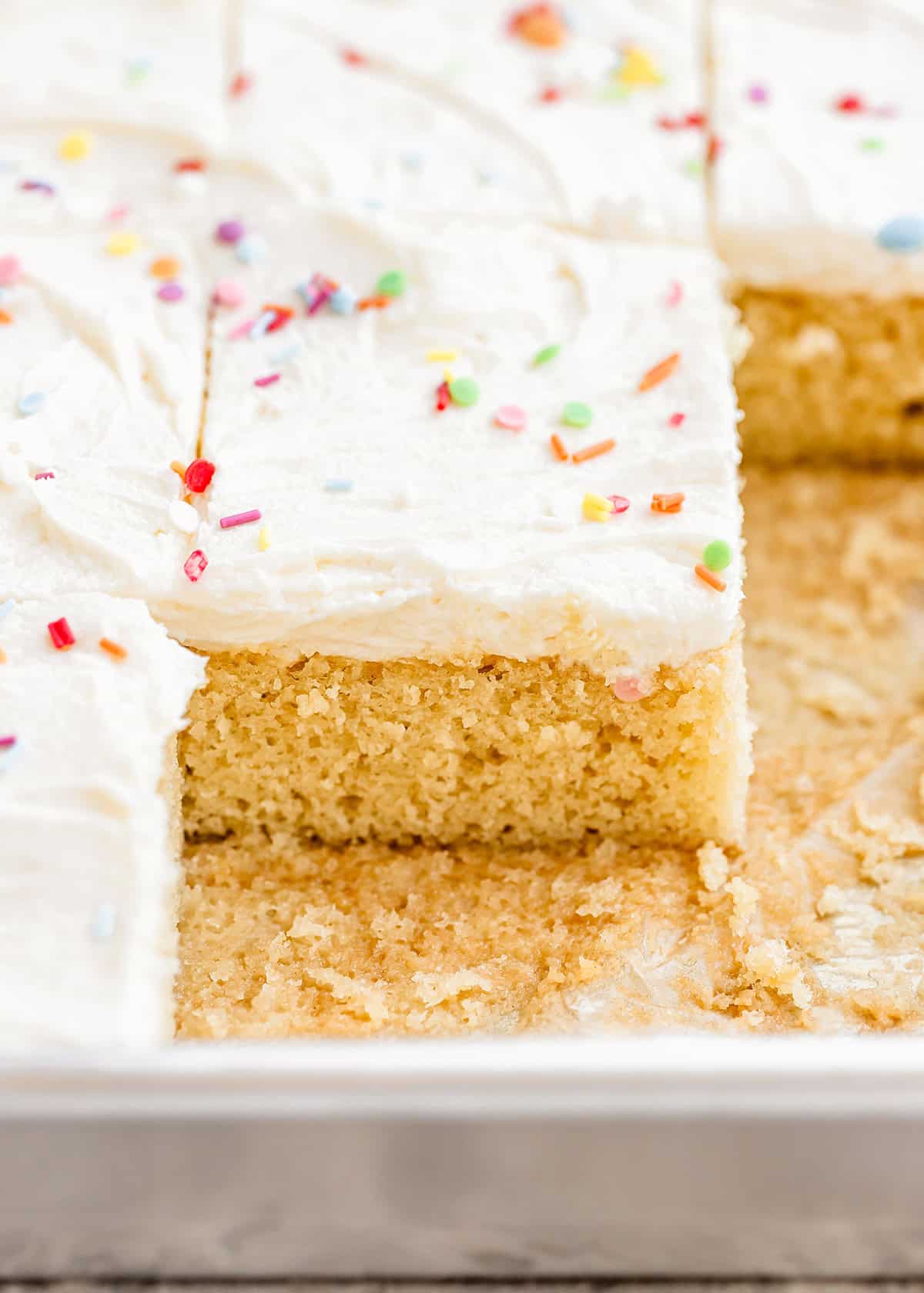 Vanilla Sheet Cake with white frosting cut into squares in a pan