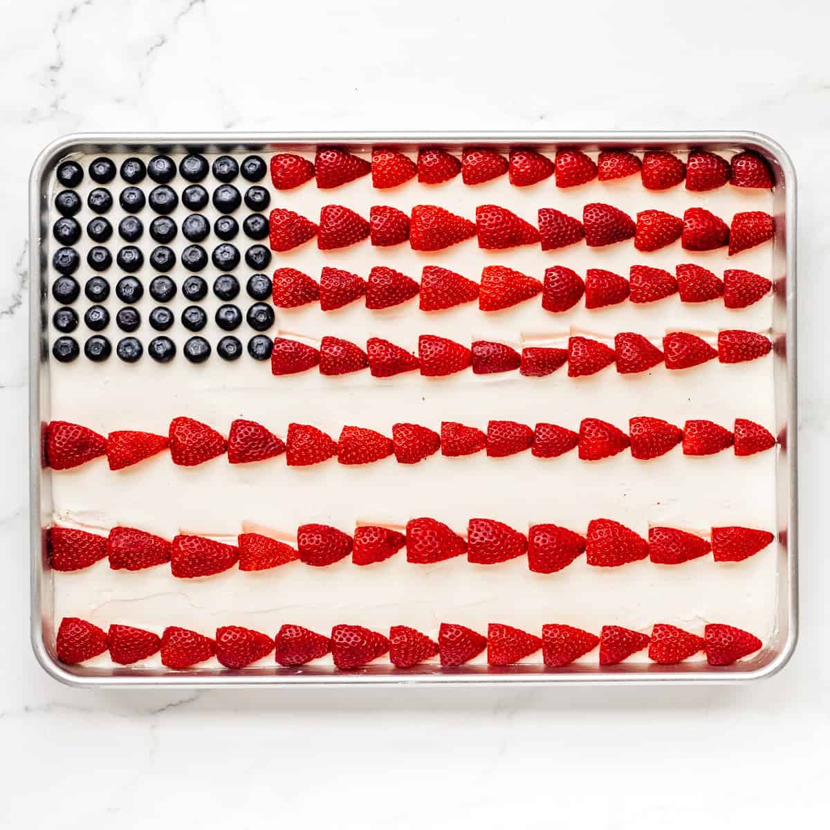flag cake assembled with blueberries as stars and strawberries as the stripes