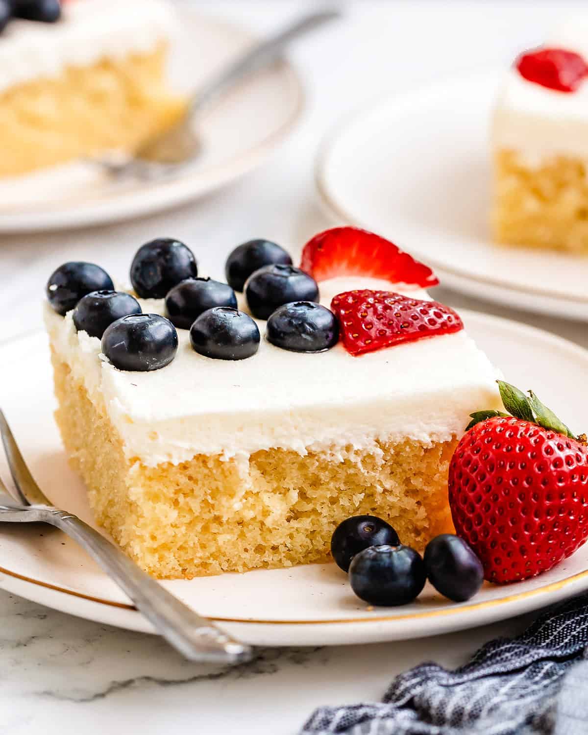 a piece of American Flag Cake on a plate with a fork and extra berries