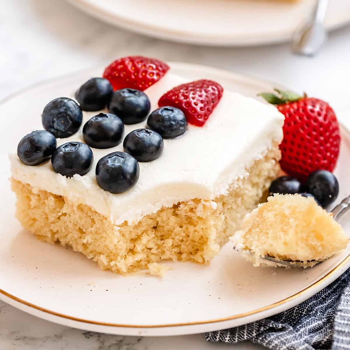 a piece of American Flag Cake on a plate with a bite taken out of it on a fork