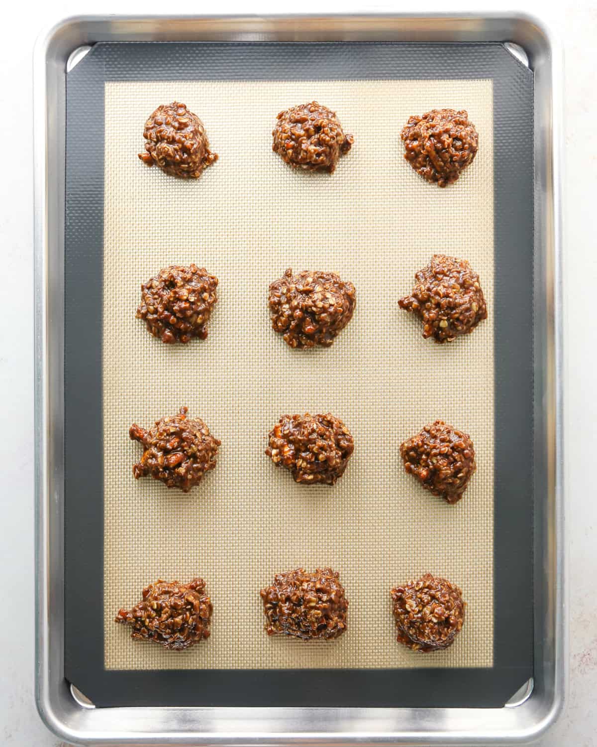 Making bird's nest cookies: overhead photo of 12 balls of cookie dough dropped onto a metal baking sheet.