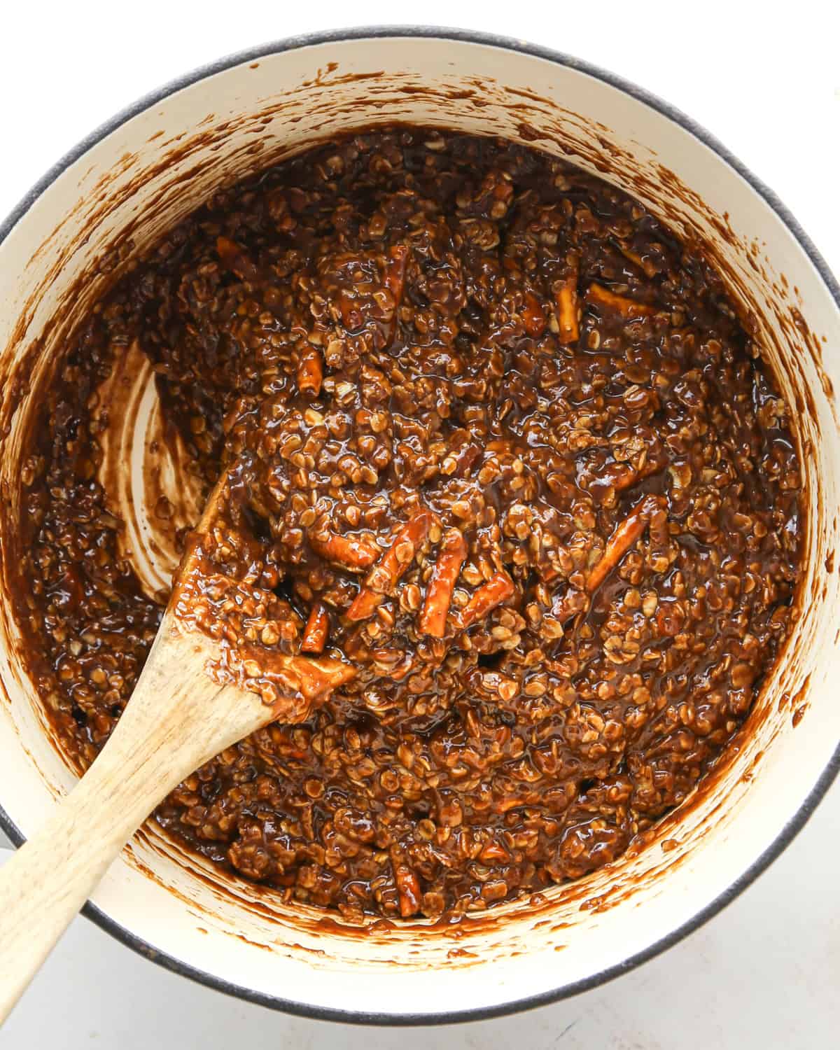 Making bird's nest cookies: overhead photo of quick-cooking oatmeal, pretzels, and other ingredients added to a large cooking pot, melted together, and being stirred with a wooden spoon.