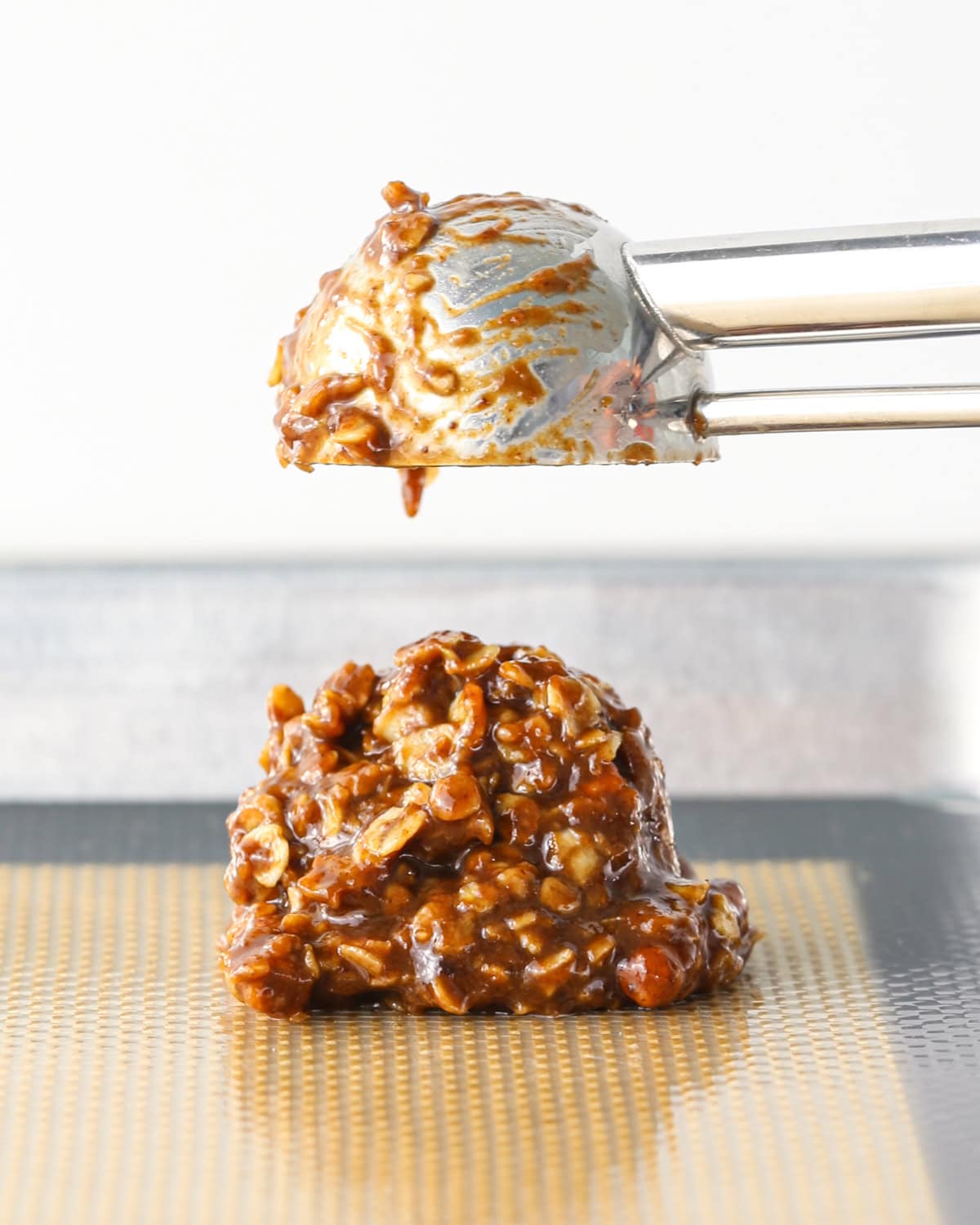 Making bird's nest cookies: close-up photo of cookie dough scooped with a cookie scoop and dropped onto a metal baking sheet.