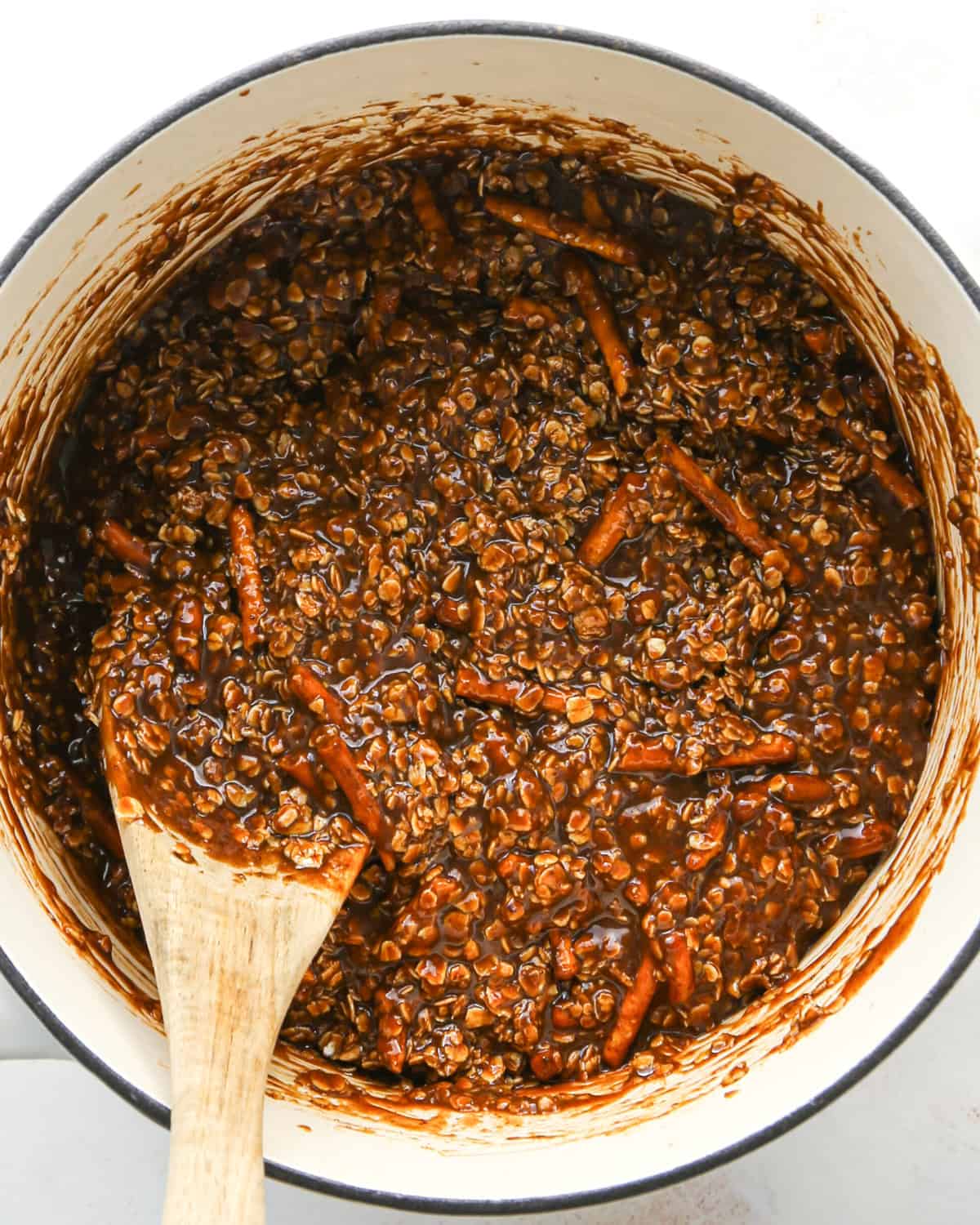 Making bird's nest cookies: overhead photo of quick-cooking oatmeal, pretzels, and other ingredients added to a large cooking pot, melted together, and being stirred with a wooden spoon.