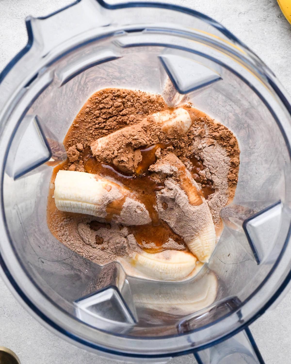 making chocolate banana smoothie: overhead photo of all ingredients sitting in a blender ready to blend.