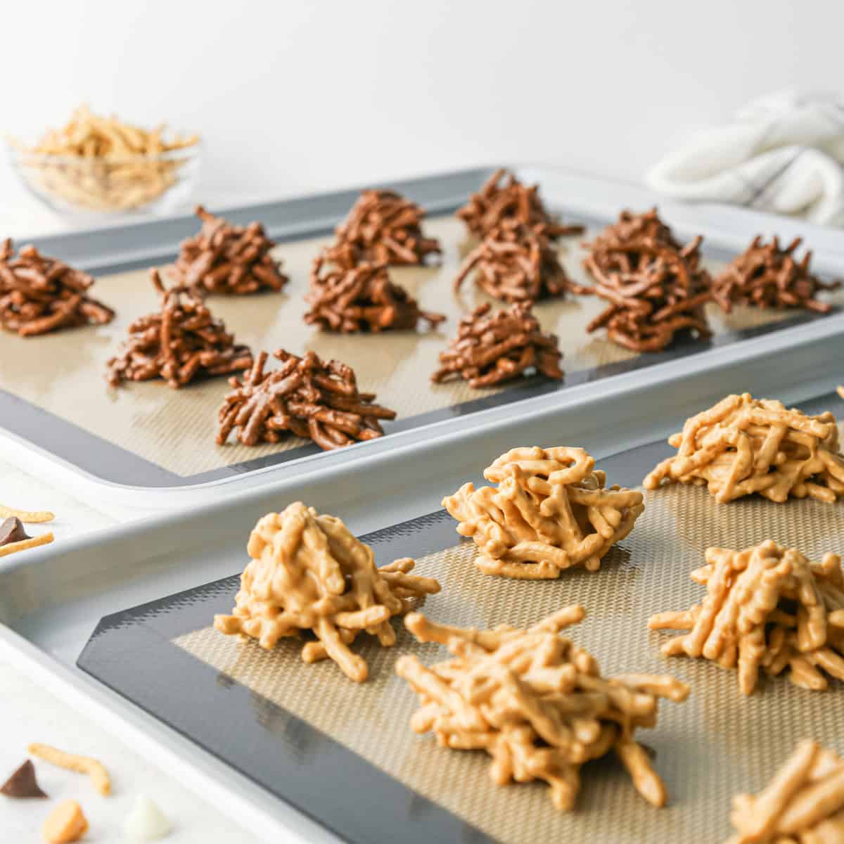 Making Haystack Cookies: front-view photo of 2 baking sheets filled with 2 varieties of haystack cookies (white chocolate and semisweet chocolate)