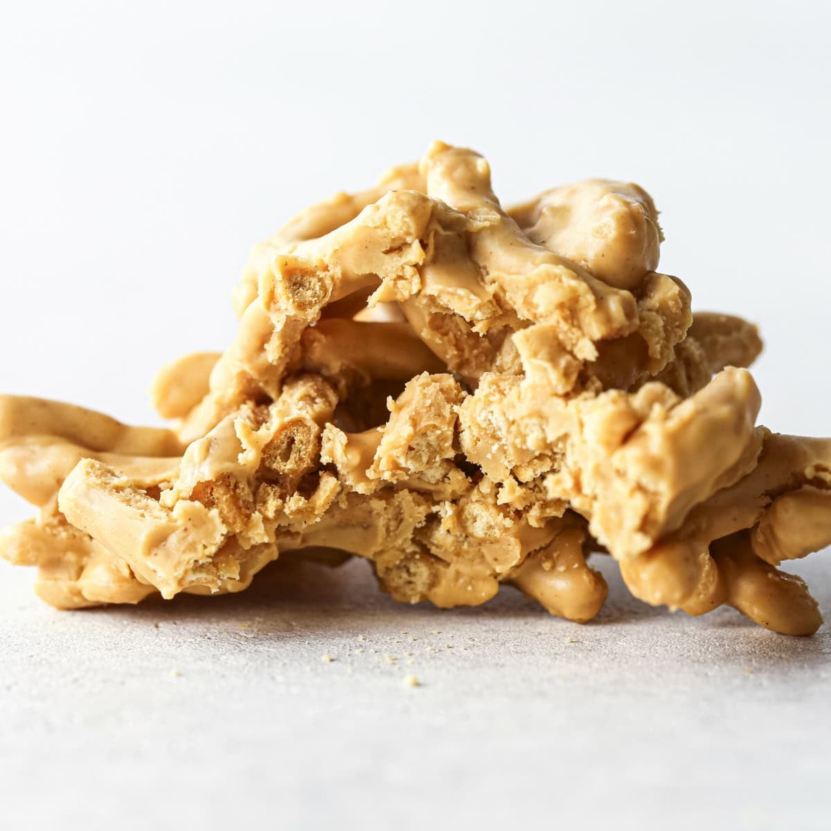 Making Haystack Cookies: close-up photo of a white chocolate haystack cookie with a bite taken out and sitting on a light-colored surface.