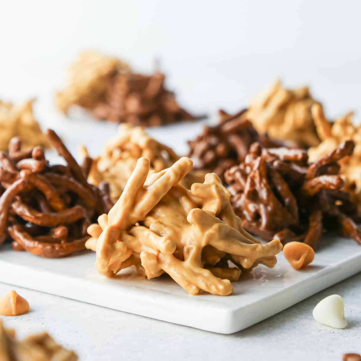 Close-up of peanut butter haystack cookies made with crunchy chow mein noodles, with chocolate and butterscotch varieties in the background.