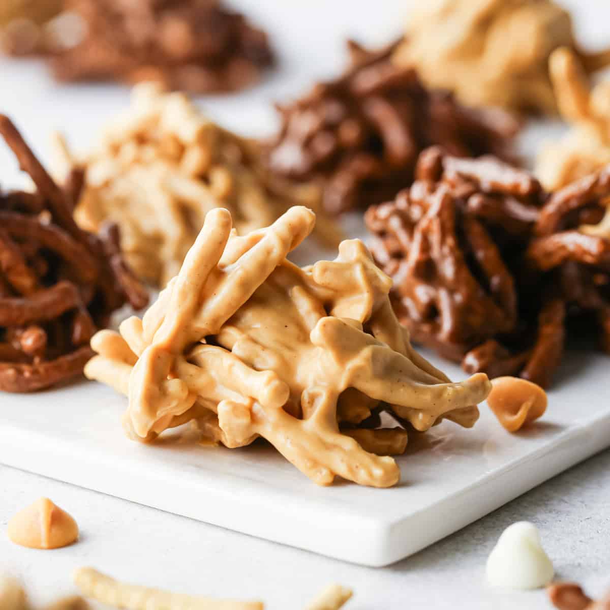 Close-up of peanut butter haystack cookies made with crunchy chow mein noodles, with chocolate and butterscotch varieties in the background.