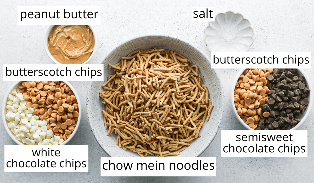 Overhead photo of the ingredients for Haystack Cookies including chow main noodles, white chocolate chips, butterscotch chips, peanut butter, salt, butterscotch chips, and semisweet chocolate chips.