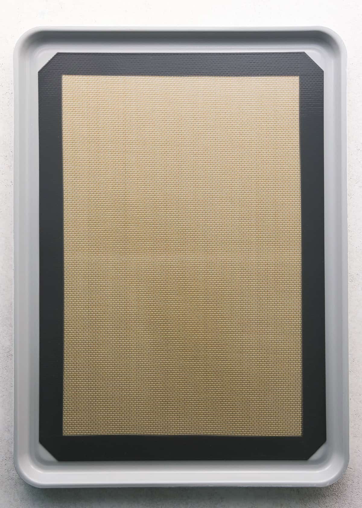 Making Haystack Cookies: overhead photo of a silicone sheet sitting on top of a metal baking sheet on a light-colored surface.