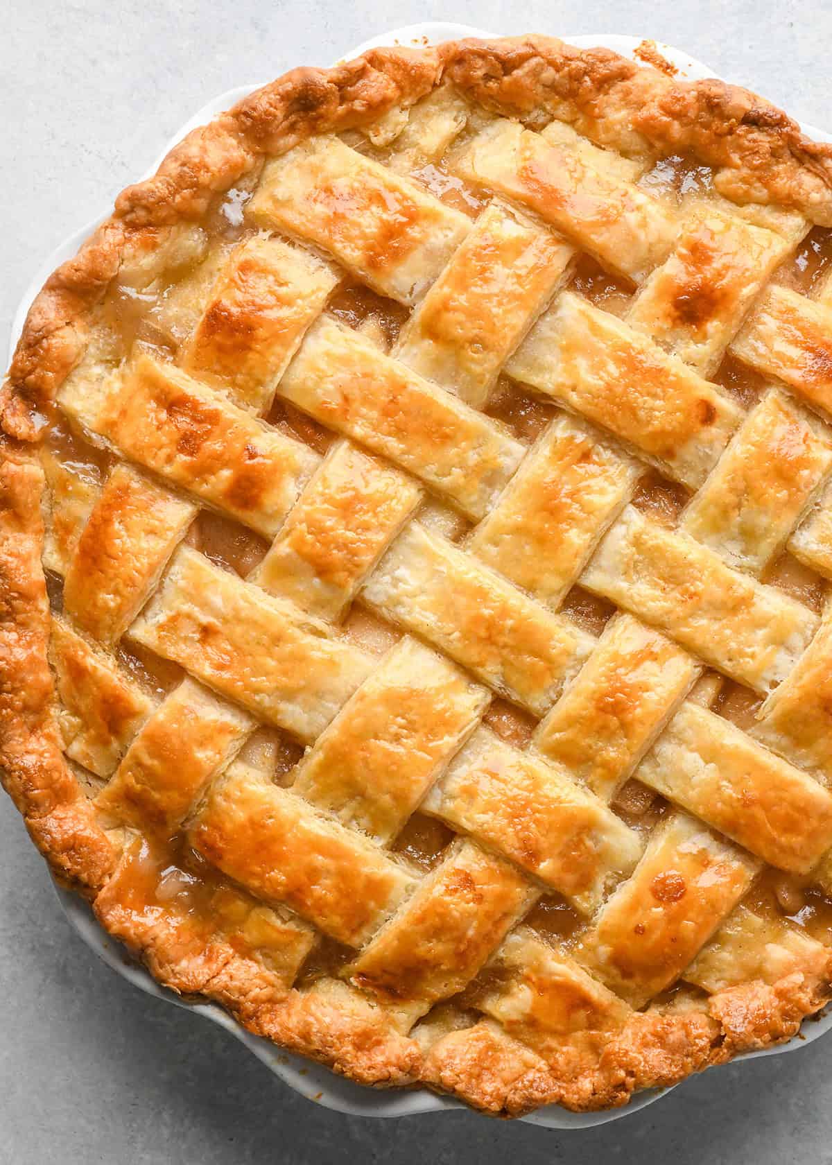 a pie with a lattice pie crust after baking on a gray surface