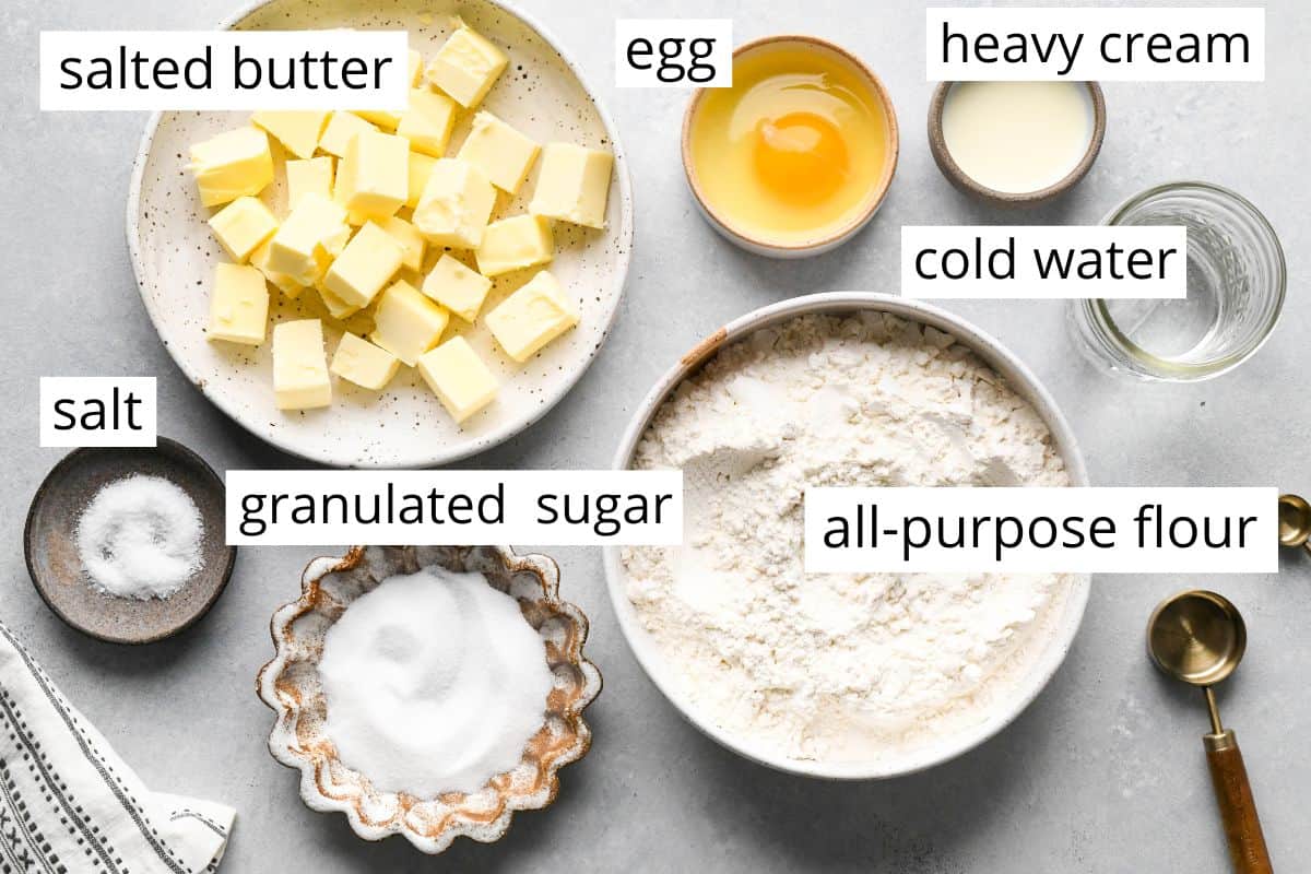 overhead photo of the ingredients in this Lattice Pie Crust recipe like butter, flour, sugar, egg, water, heavy cream and salt. 