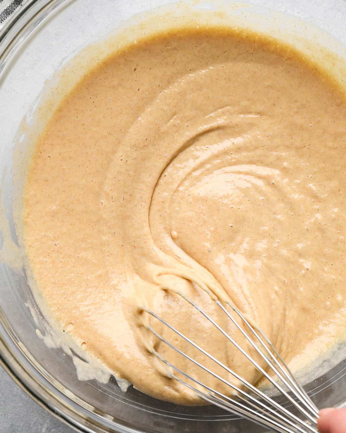 How to Make Oat Flour Pancakes - batter in a glass bowl after thickening with a whisk in it to show the texture