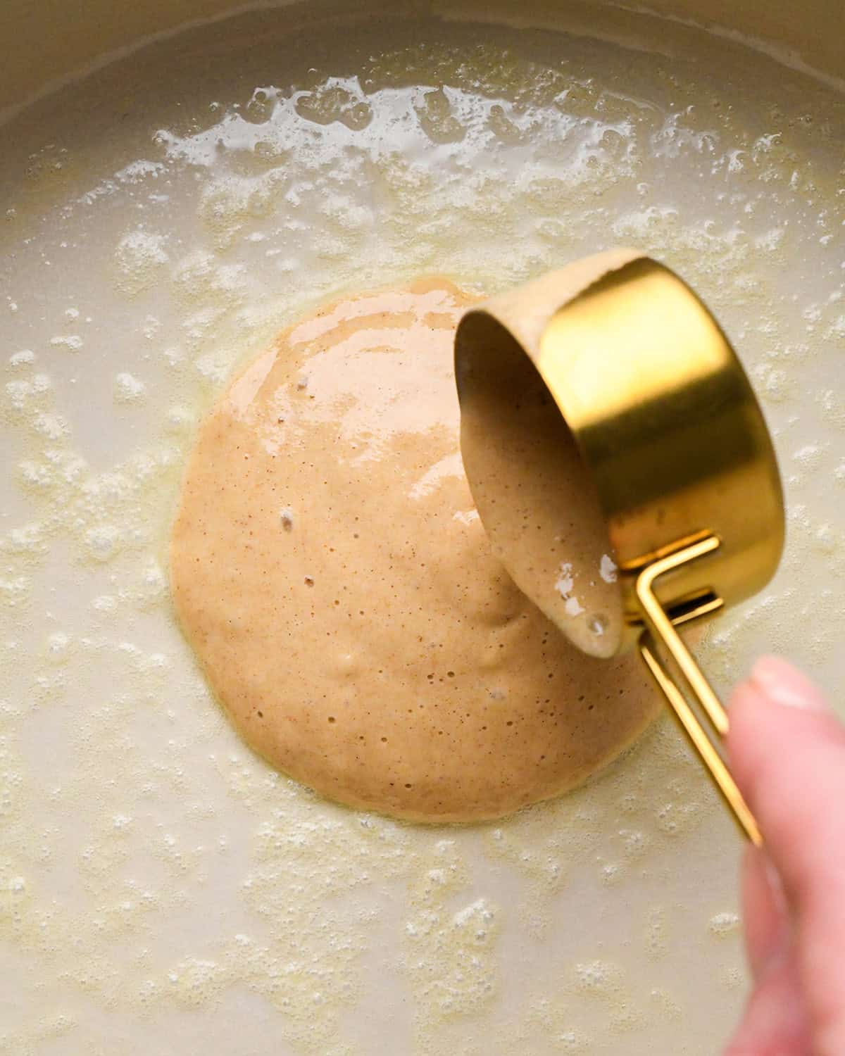 How to Make Oat Flour Pancakes - batter being poured onto buttered pan