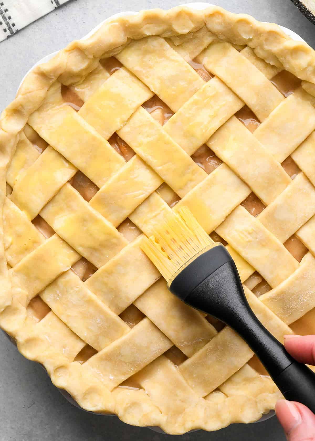 a silicone brush spreading egg wash on pear pie