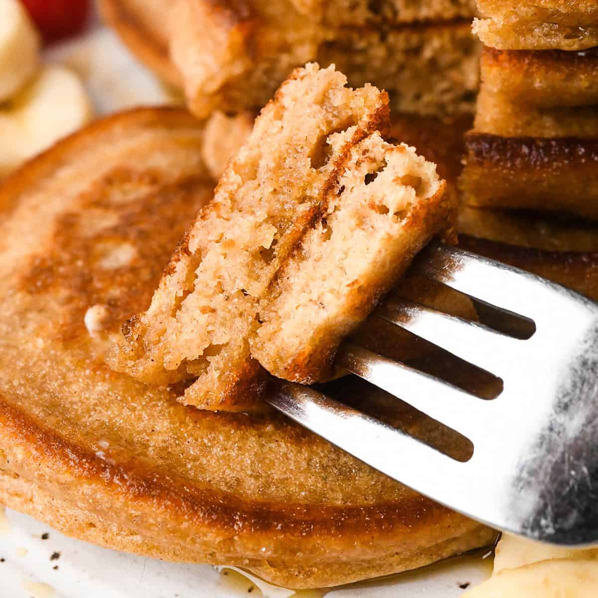 close up of a fork with two pieces of Oat Flour Pancakes on it on top of another pancake
