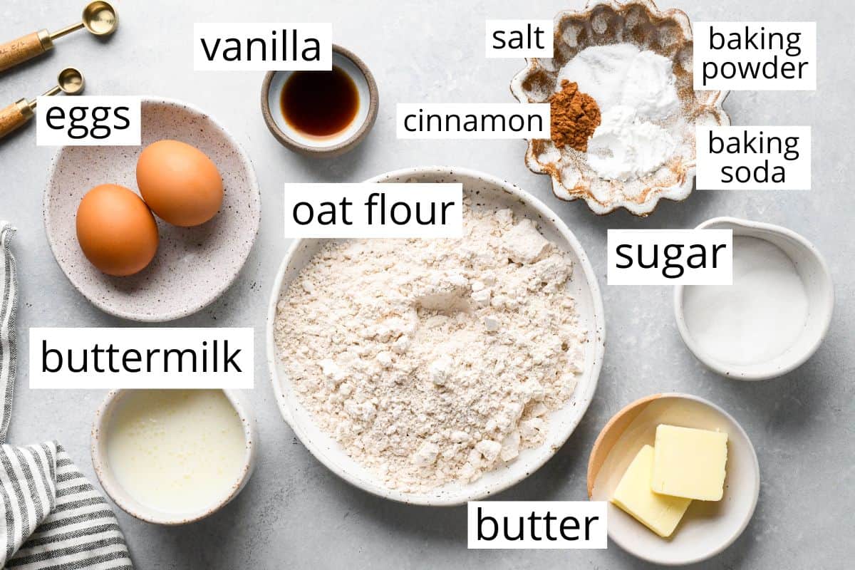 overhead photo of the labeled ingredients in this Oat Flour Pancakes recipe like oat flour, eggs, buttermilk, sugar, vanilla and butter