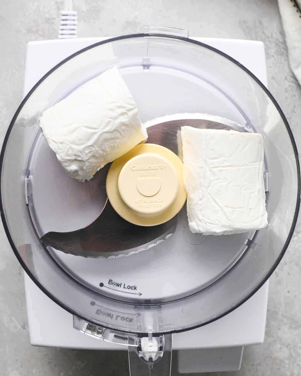 a log of goat cheese cut in half in a food processor