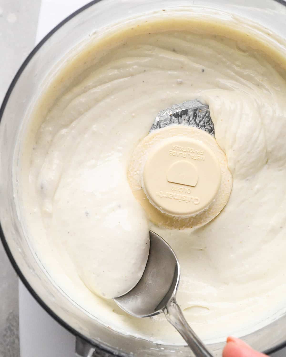 final whipped goat cheese mixture in a food processor with a spoon