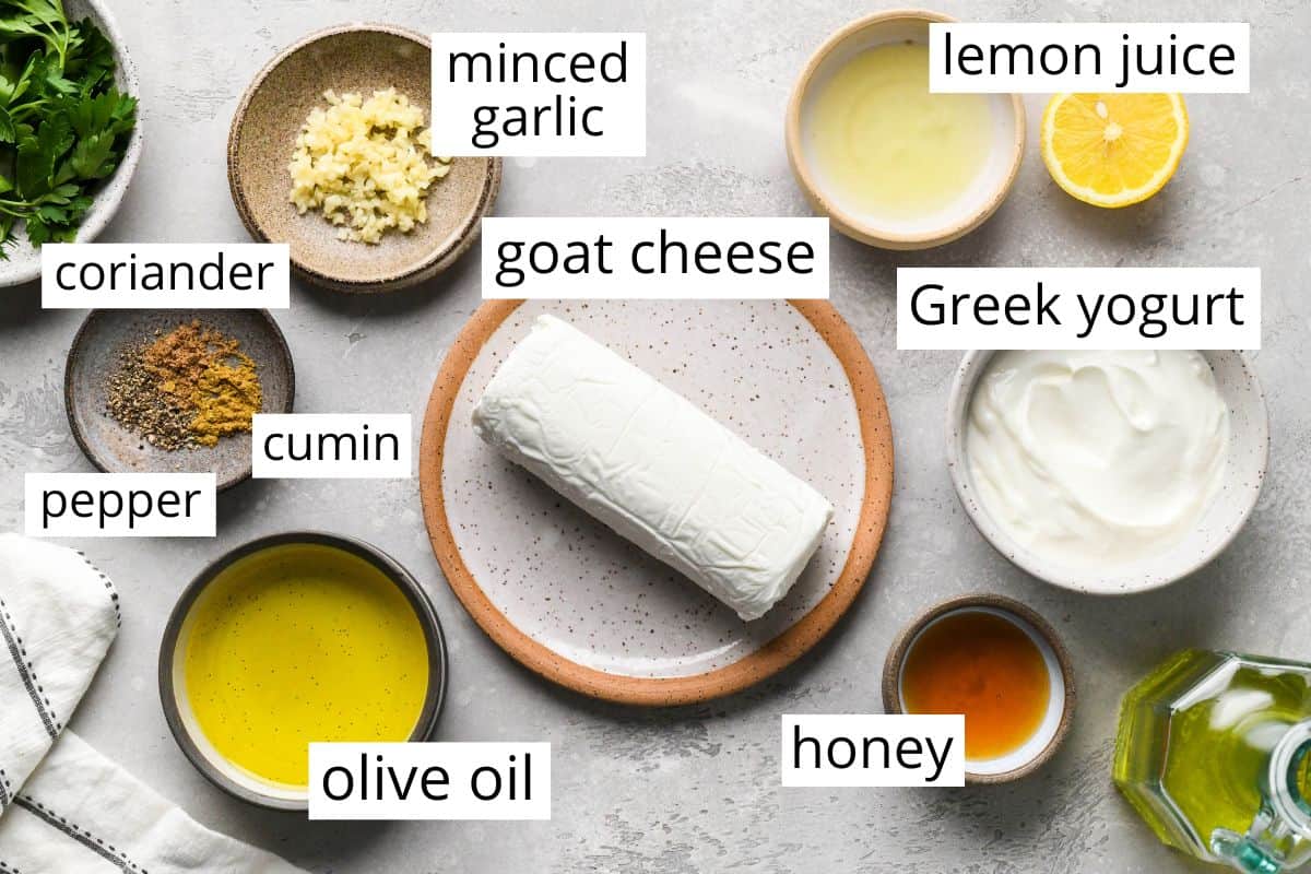 overhead photo of the labeled ingredients in this Whipped Goat Cheese Dip recipe like goat cheese, olive oil, honey, greek yogurt, garlic and spices