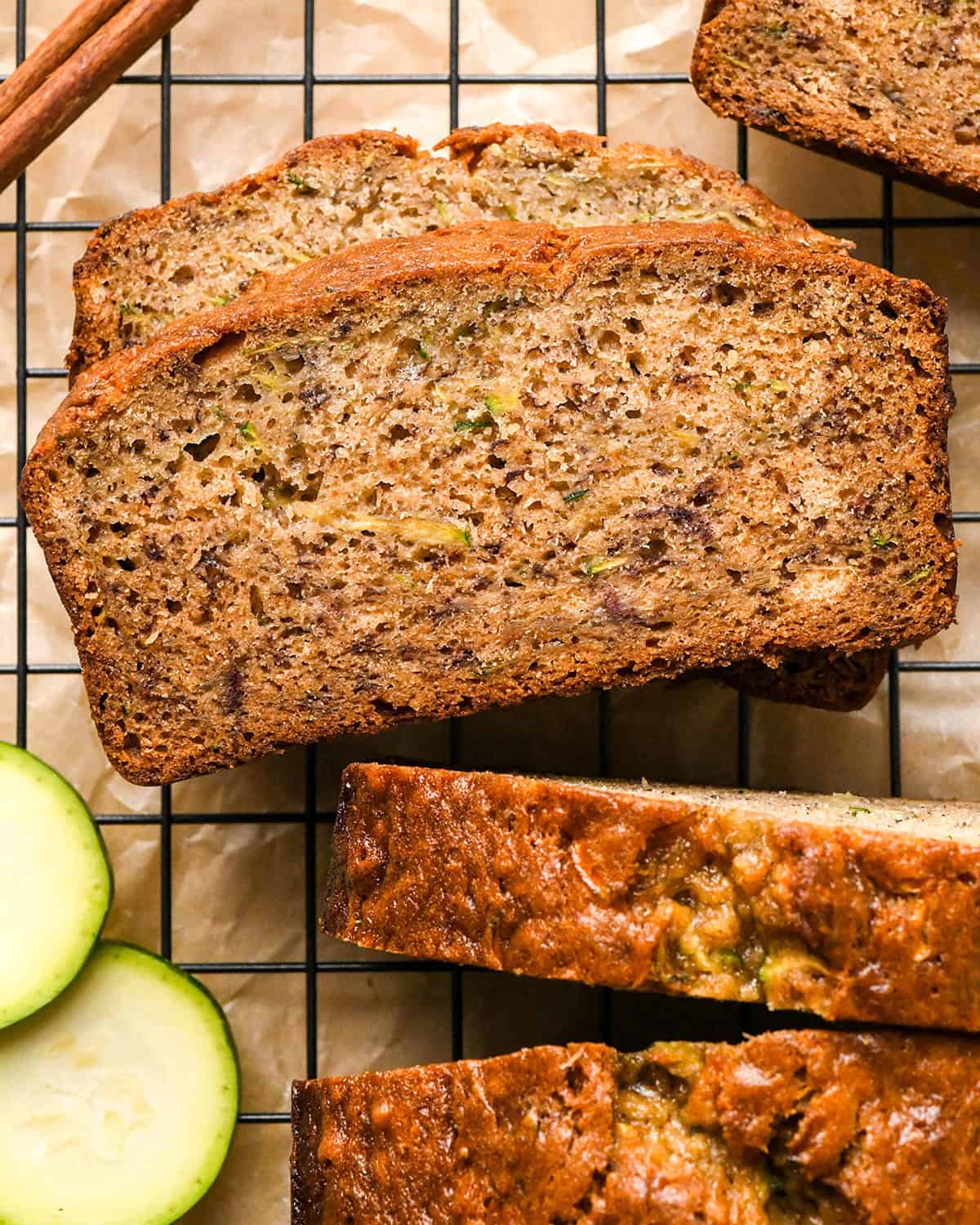 4 slices of banana zucchini bread on a wire rack on parchment paper styled with two slices of zucchini