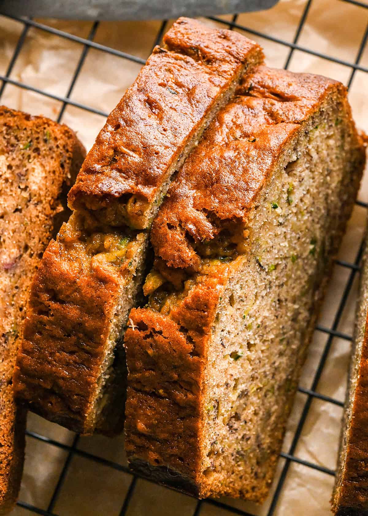 2 slices of Banana Zucchini Bread on a wire cooling rack on parchment paper