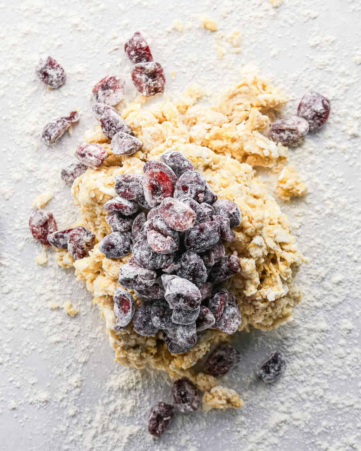how to make cherry scones - scone dough on a floured surface and floured cherries on top 