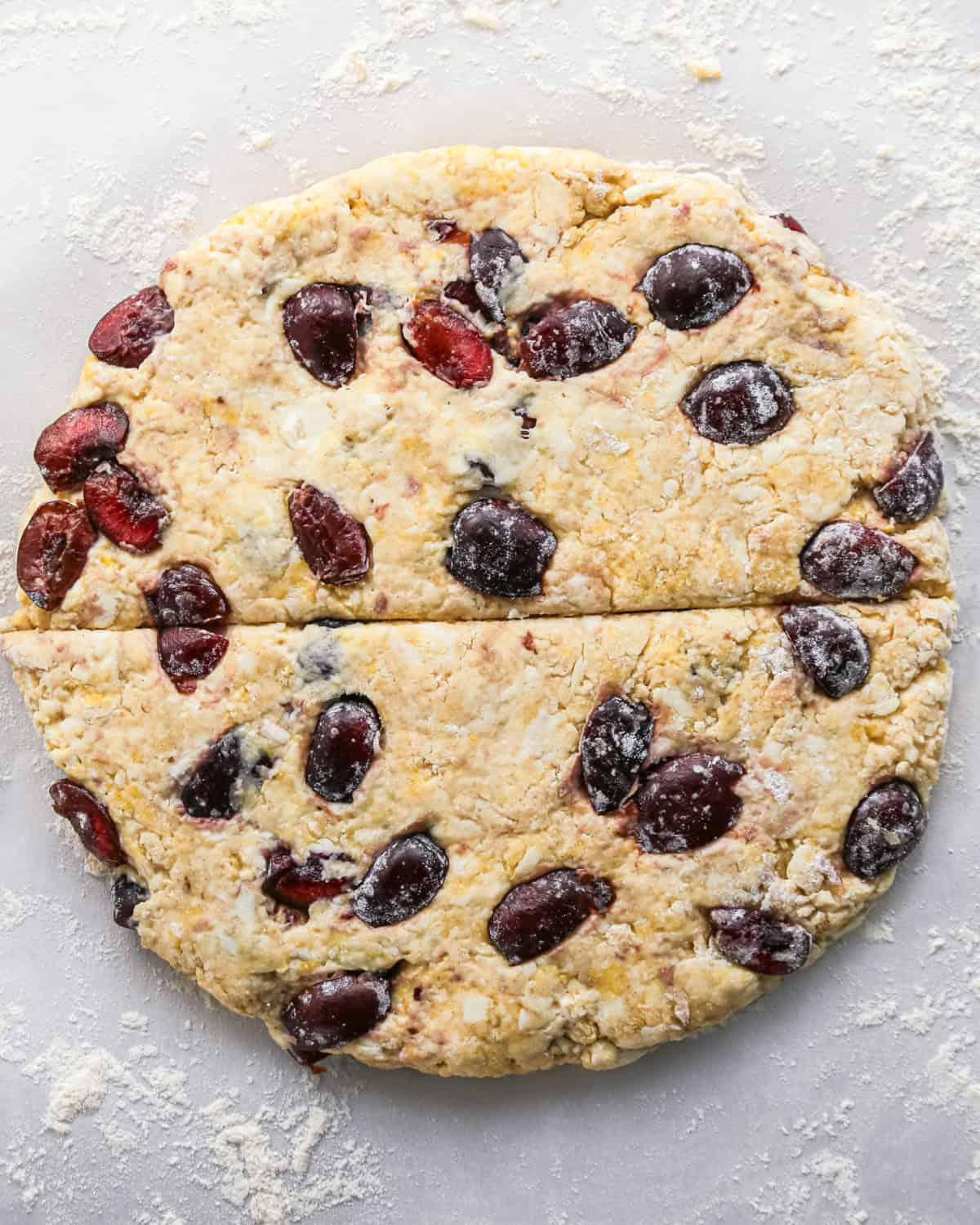 how to make cherry scones - scone dough with cherries formed into a round disc cut in half