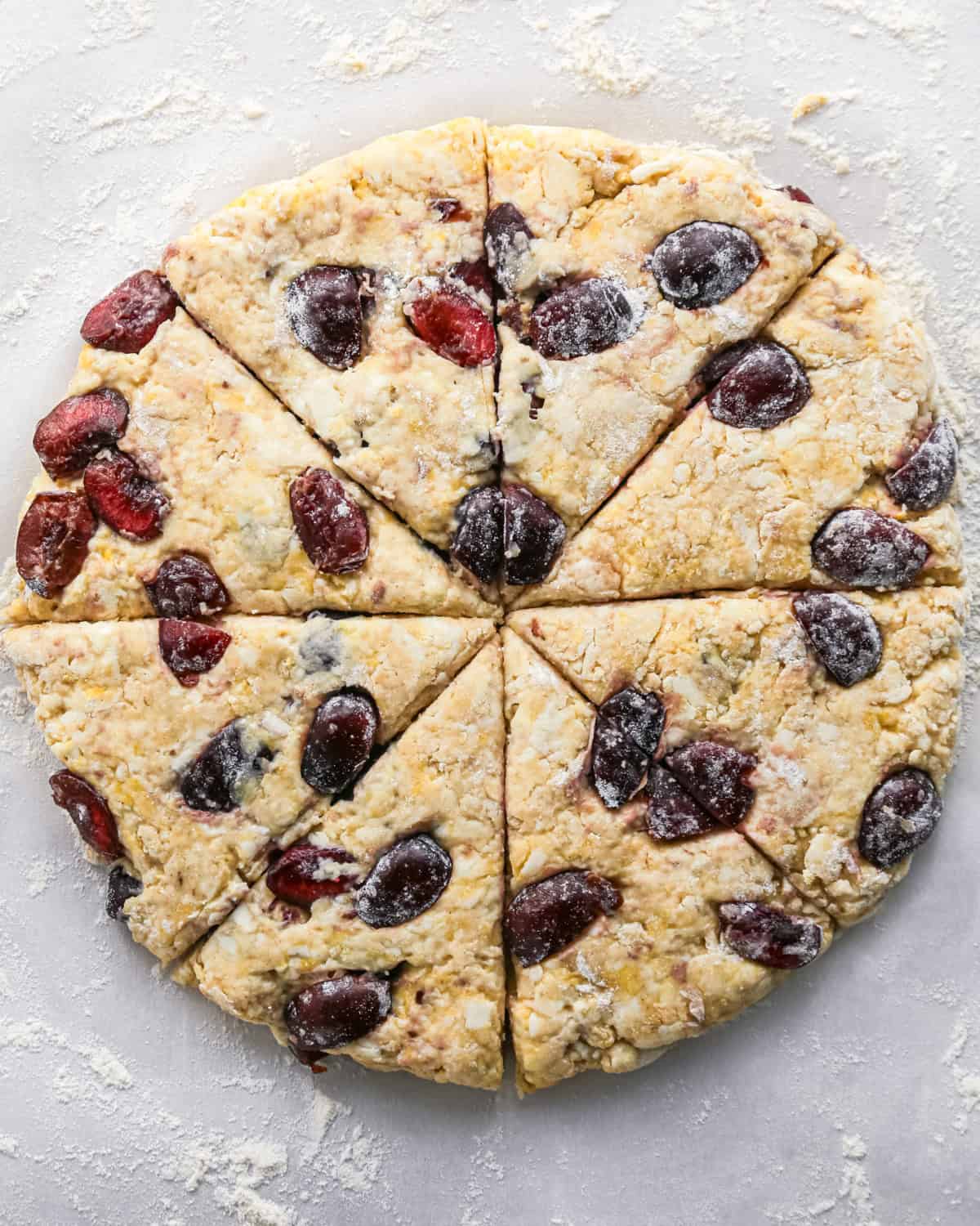 how to make cherry scones - scone dough with cherries formed into a round disc cut in eighths