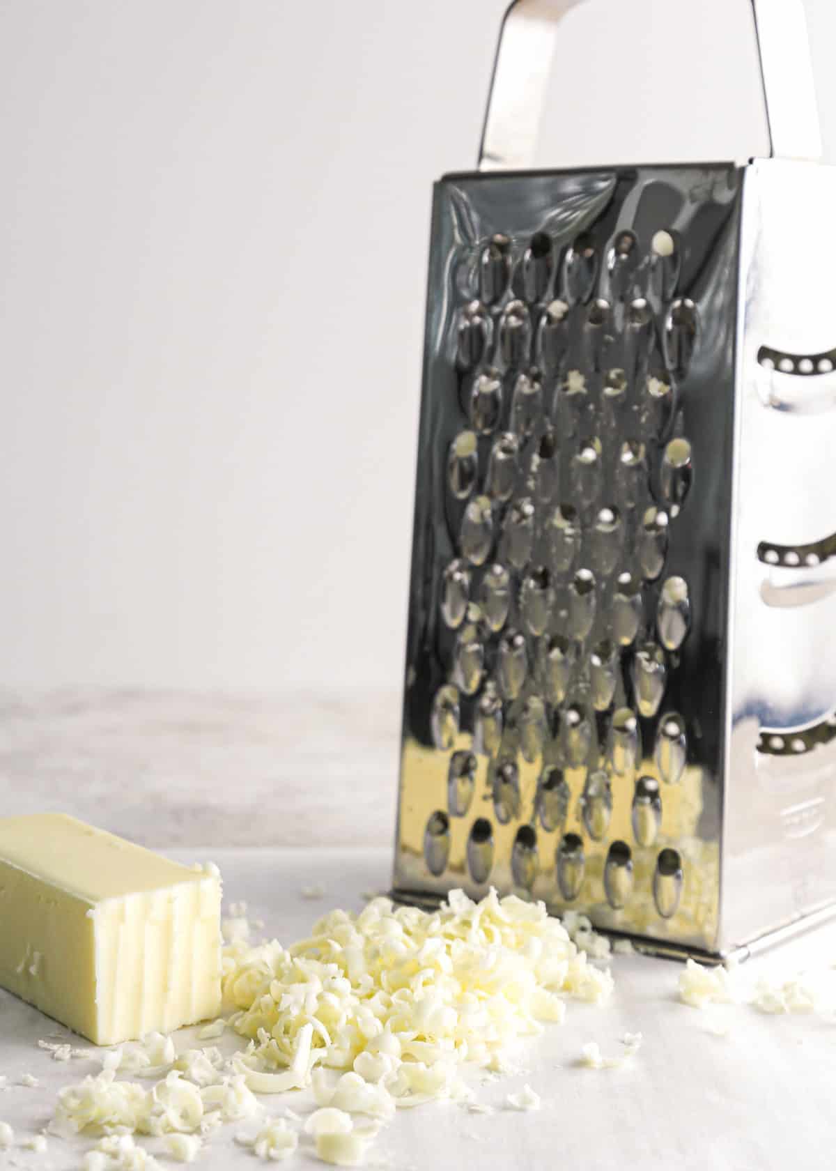 grated frozen butter by a silver box grater and half a stick of frozen butter