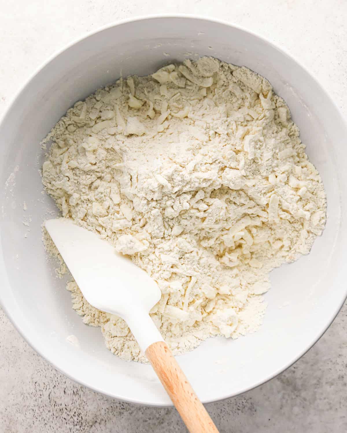 how to make cherry scones - grated frozen butter stirred into dry ingredients with a white and wood spatula